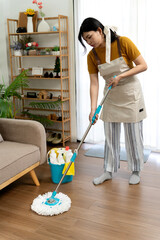 Young woman cleaning a home's floor with a mop cleaning the house