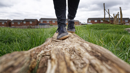 Woman walking on a wood log in city park. Leisure activity for mental health.