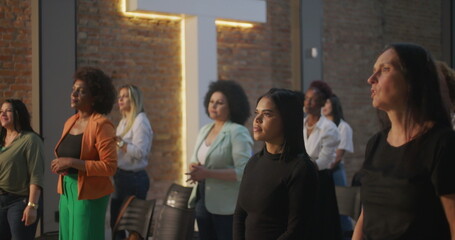 Women of various ethnicities standing in prayer during a spiritual gathering, expressing unity,...