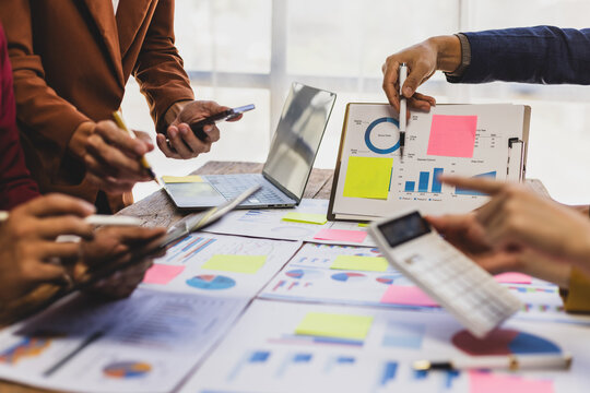 Business people analyzing financial statistics working together in office. Business professionals are working together in office, analyzing financial statistics and data on chart and graph. - Powered by Adobe