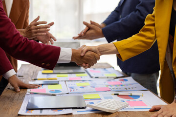 Business people shaking hands after successful meeting. Two business people shaking hands while their colleagues are clapping, after reaching an agreement during a productive meeting.