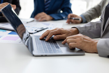 Businessman analyzing financial chart and report using laptop computer. Business people working together at office desk analyzing financial charts and reports using laptop.