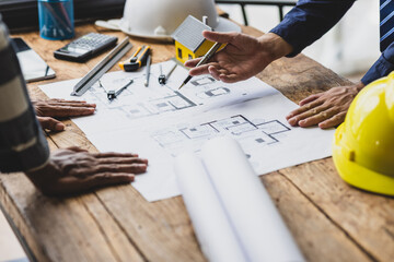 Architects discussing at architectural plans on a table. Architect and contractor engineer working together in office.