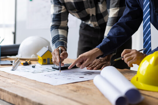 Architects discussing at architectural plans on a table. Architect and contractor engineer working together in office.