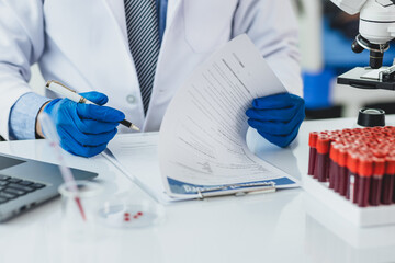 Scientist analyzing blood test results in a laboratory. Scientist in a lab carefully examines blood test results, focusing on precision and attention to detail in medical analysis.
