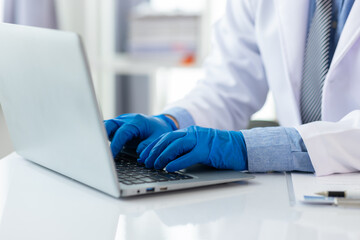 Scientist is working at a laboratory bench, typing on a laptop computer keyboard.