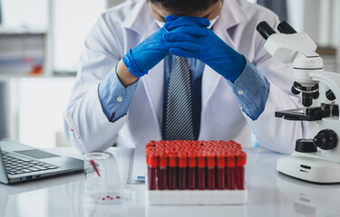 Medical scientist feeling stressed while working using microscope in laboratory, feeling stressed while doing some research, failed experiment.