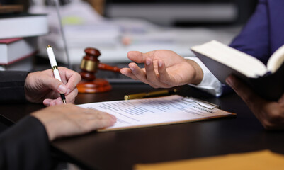 Lawyer holding law book explaining legal issues to client during a meeting. Lawyer gives legal advice to a client in an office, discussing a contract.