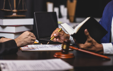 Lawyer holding law book explaining legal issues to client during a meeting. Lawyer gives legal advice to a client in an office, discussing a contract.