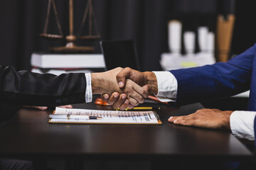 Lawyers shaking hands after signing contract in law office.