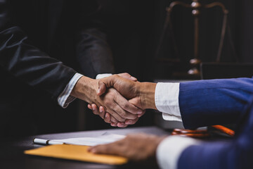 Lawyers shaking hands after signing contract in law office.