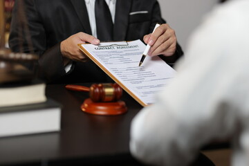 Lawyer reviewing contract agreement with legal documents, Discussing contract agreement at desk with legal document.