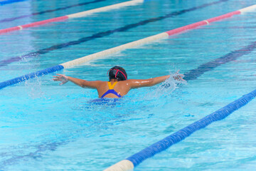 Swimmer child swims butterfly swimming style in a race swimming pool. Water sports and competition,...