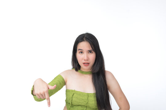 Teenage Southeast Asian girl points downward with urgency, frustration on her face, clearly displeased or warning someone. Isolated on a light background.
