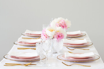 Elegant wedding table setting with pink peonies, gold cutlery, and crystal glassware, creating a romantic and sophisticated atmosphere.