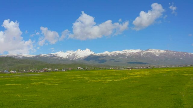 Aerial footage mountains and green field. Aragats mountain in Yerevan, Armenia. Drone fly over green field ant mountain with snow on top. Amazing view. Tourist concept.