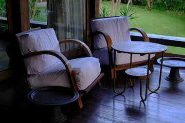 Two Wooden Armchairs with White Cushions on Villa Terrace with Coffee Table