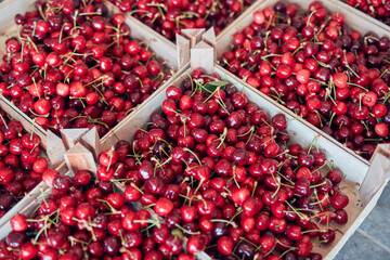 Fresh red sweet cherries in wooden crates prepared for sale on a market.