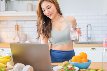fit Asian female in sportswear enjoys a colorful fruit shake and fresh mineral water while...