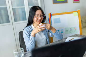 Young Thai Woman Drinking Coffee During Online Business Video Call..