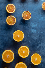Orange and blood orange slices creating a pattern on dark blue background