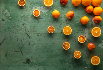 Fresh oranges and blood oranges decorating a green wooden table