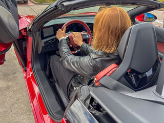 Redhead driver makes peace sign in red electric convertible