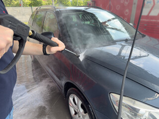Closeup of male driver washing his car with contactless high pressure water jet