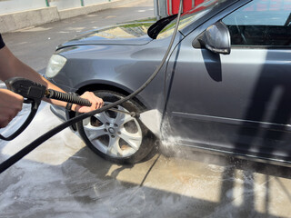 Closeup of male driver washing his car with contactless high pressure water jet