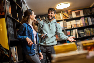 Two students read a book in the library together.