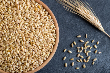 Wheat grains in wooden bowl and ears on top view
