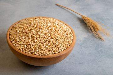 Wheat grains in wooden bowl and ears on bright background,top view