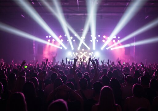 Concert crowd enjoys performance with lights, stage and arms raised up