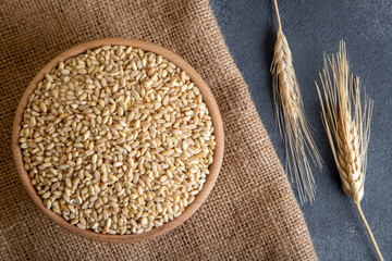 Wheat grains in wooden bowl and ears on burlap sack,top view