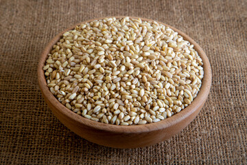 Wooden bowl in wheat grains on burlap sack