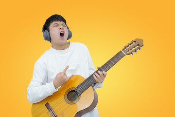Obraz premium young musician playing acoustic guitar while wearing headphones on orange background
