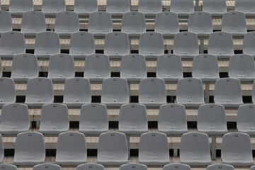 This detailed overview showcases a series of empty gray plastic stadium seats which are...