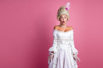 Elegant young woman tied with rope dressed as a baroque aristocrat against a pink background