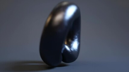 A dark gray, metallic ring with a complex, intertwined shape.  Its form is smooth, yet textured, creating a sense of depth and intricacy