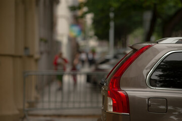 A car is parked on a busy street as pedestrians stroll by, capturing the vibrant urban life and the...