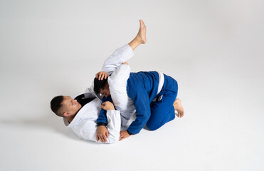 Two jiu jitsu athletes grappling on white background