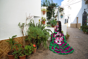 Young, pretty, brunette, flamenco dancer, showing her beautiful dress, sitting on a chair with her...