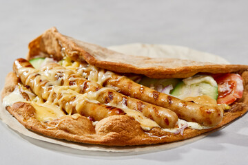 Gyros with grilled sausages on flatbread, creamy sauce close-up, vibrant, minimalistic composition
