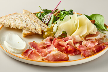 Gourmet Antipasto Selection with Prosciutto, Cheese, and Olives on Minimalistic Plate