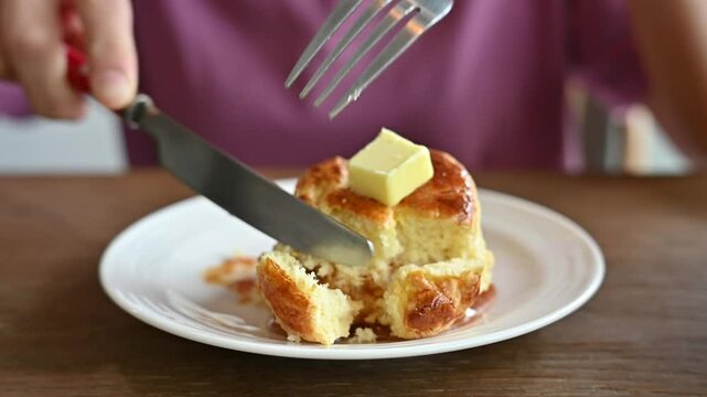 Woman using knife and fork for cut a piece of butter scone for eat. A butter scone is a type of quick bread popular in the United Kingdom and Ireland.