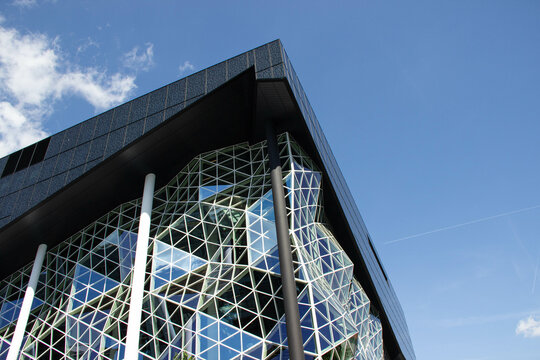 Modern building with curved glass facade and white columns in Europe, showcasing complex architecture and innovative contemporary design.