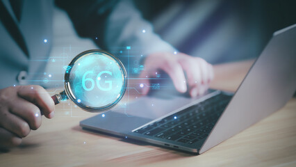 Businessman holding a magnifying glass for search 6G technology and futuristic advancement, future technology 6G network internet of thinks connection communication, high-speed internet network signal