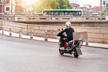 Delivery rider navigating Shanghai streets on a scooter during daytime