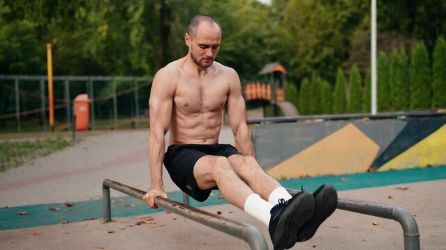 A muscular man performs dips on parallel bars in a park. He focuses on proper form and controlled movements, showcasing strength and dedication to fitness. tranquil atmosphere of the workout.
