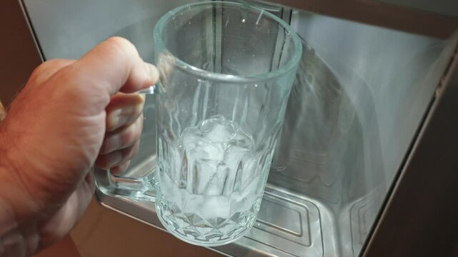 Filling large mug with ice from a fridge ice dispenser 